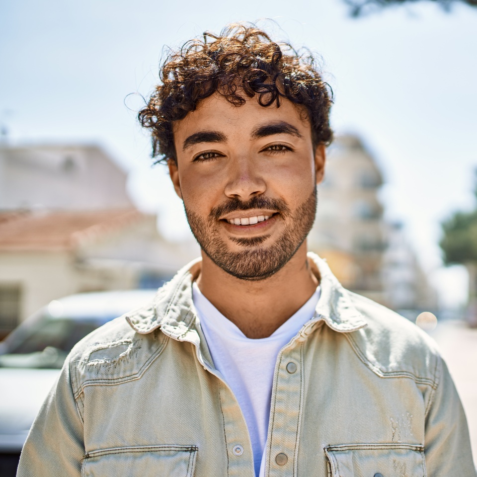 Handsome hispanic man with beard smiling happy outdoors on a sunny day