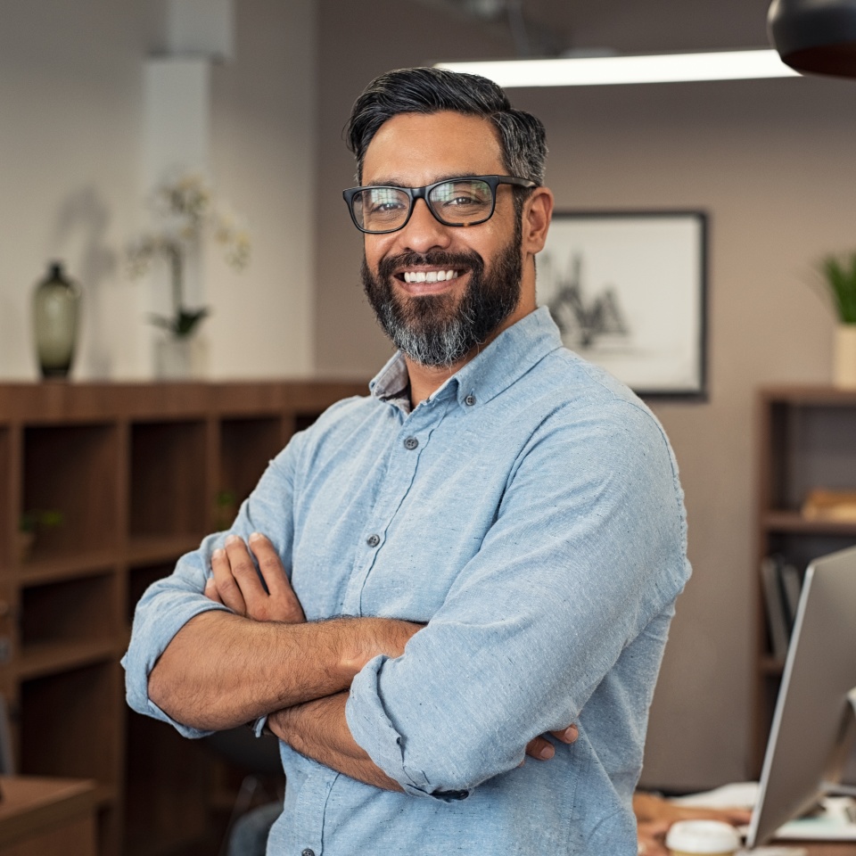 Portrait of happy mature businessman wearing spectacles and looking at camera. Multiethnic satisfied man feeling confident in a creative office. Successful middle eastern business man smiling.