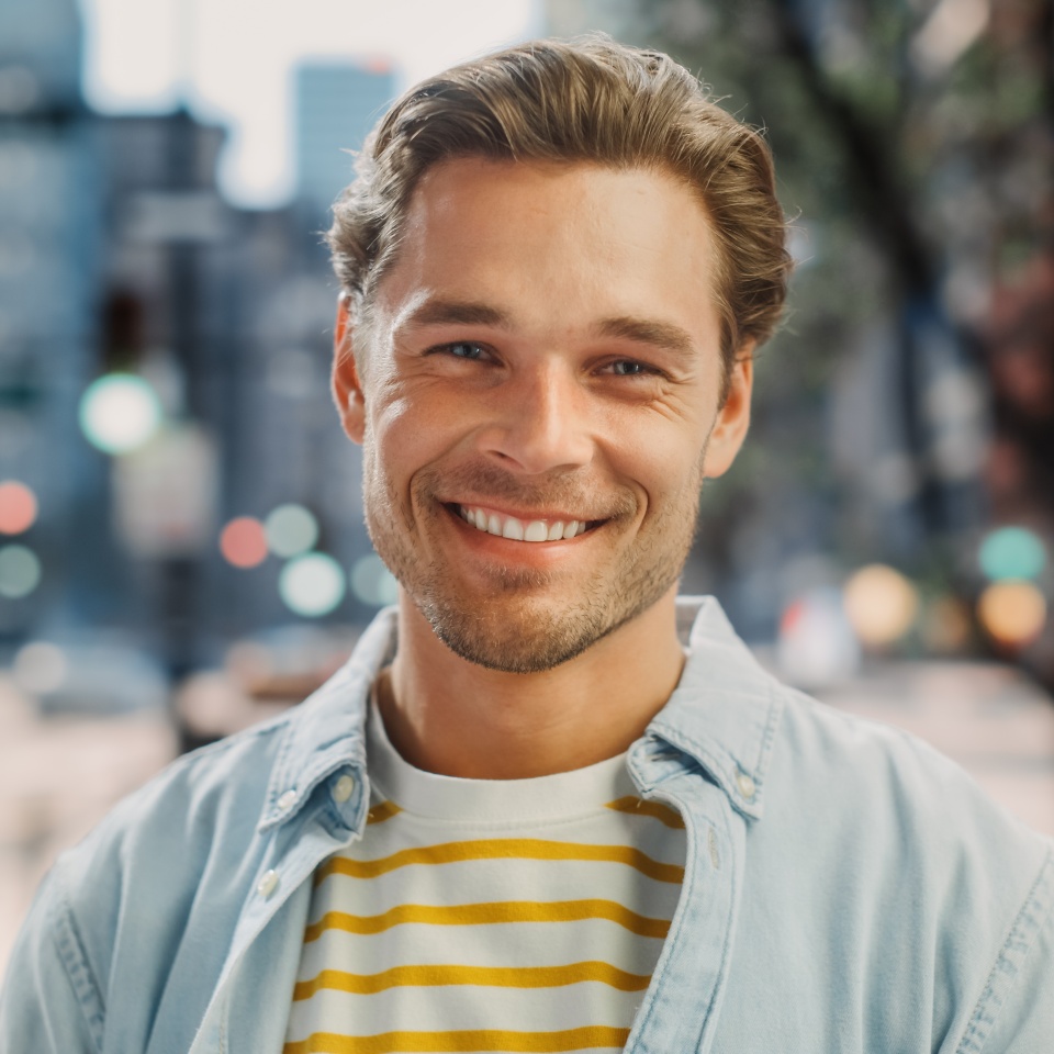 Portrait of a Happy Handsome Young Man in Casual Clothes Posing on the Street. Successful Male Model in Big City Living the Urban Lifestyle. Background with Office Buildings and Billboards.