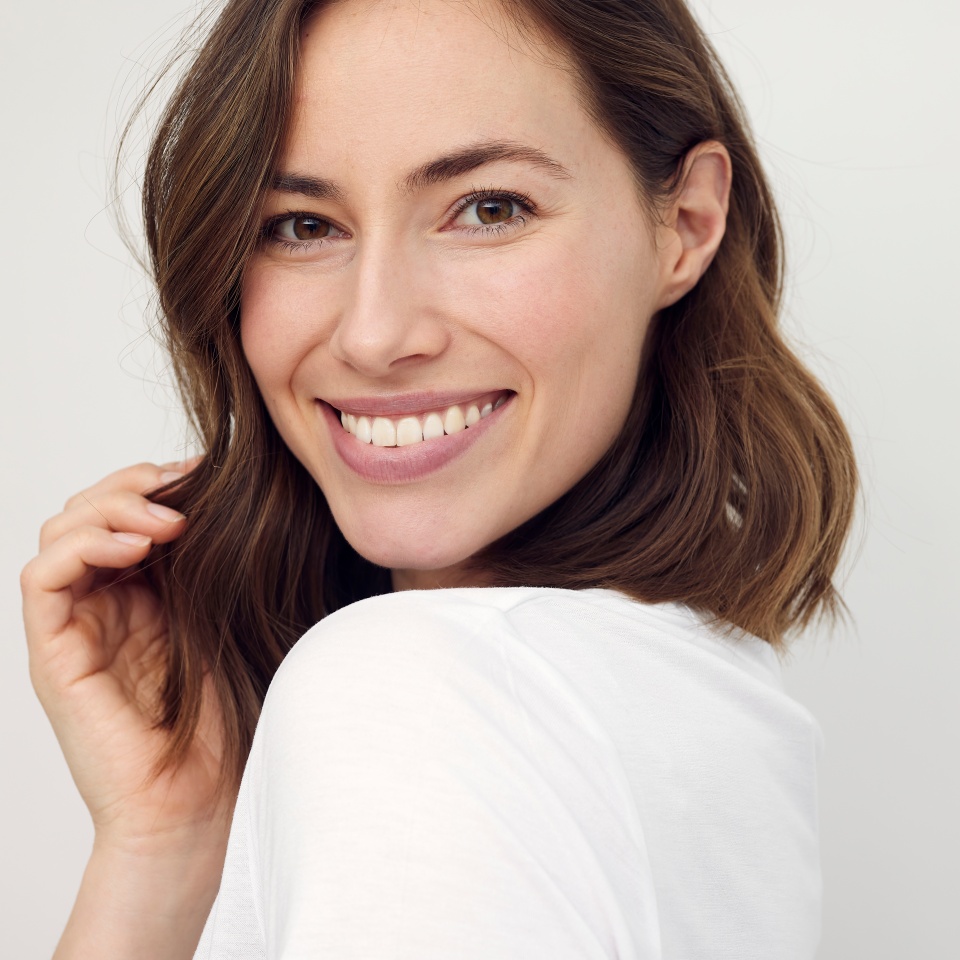 Portrait of beautiful naturally brunette woman, smiling and looking in camera with white teeth. Close-up portrait of cute female girl isolated on white background.