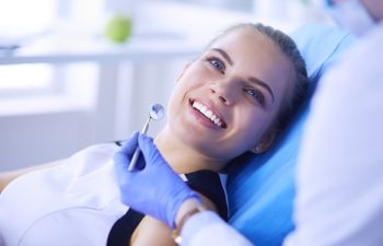 Young Female patient with pretty smile examining dental inspection at dentist office. Coronavirus COVID-19 virus pandemic
