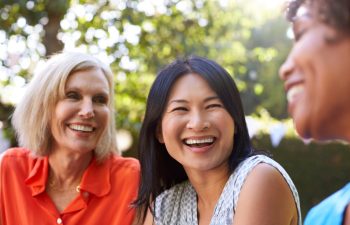 Mature Female Friends Socializing In Backyard Together